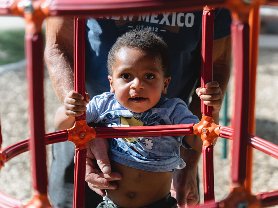 Decorative image of a very young child being held up in a jungle gym