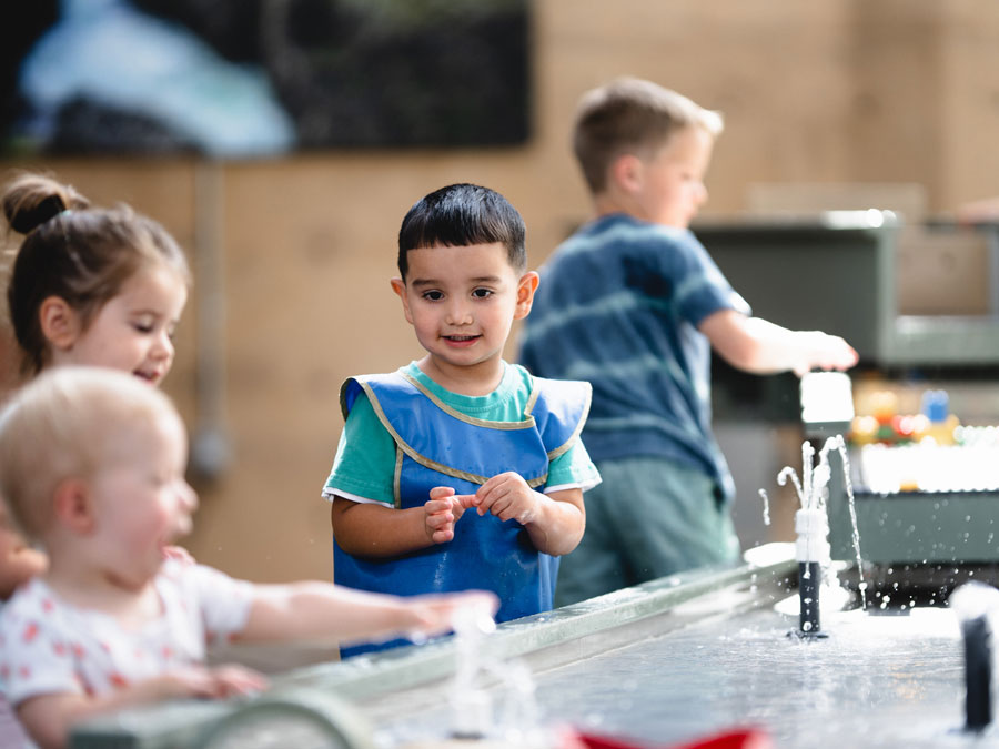 Decorative image of very young children interacting together with a water science exhibit