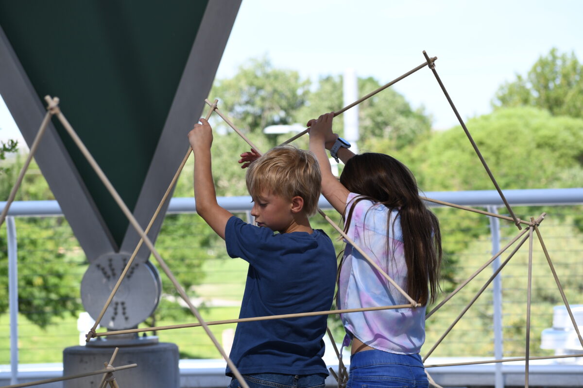 two children build structure with rods