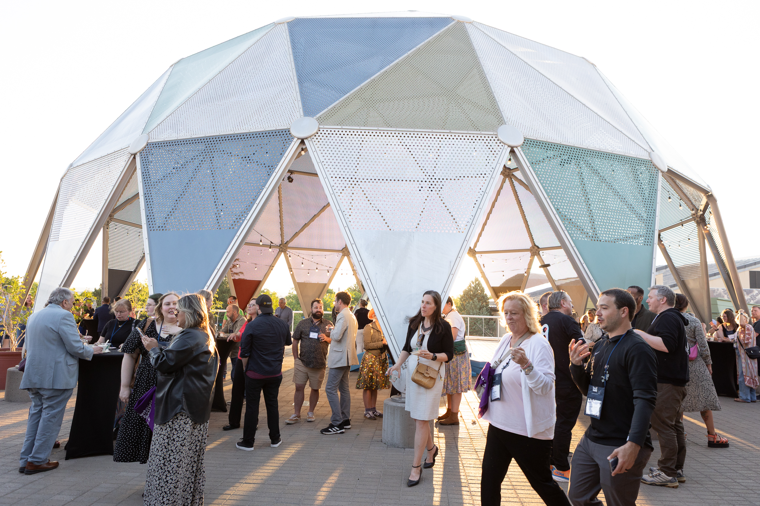 People gather at Explora’s geodesic dome during an outdoor event at sunset.